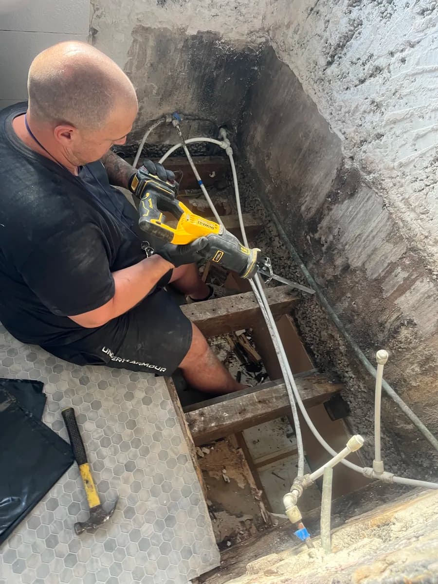 CLM Projects site lead repairing a bathroom floor while the AI runs the office